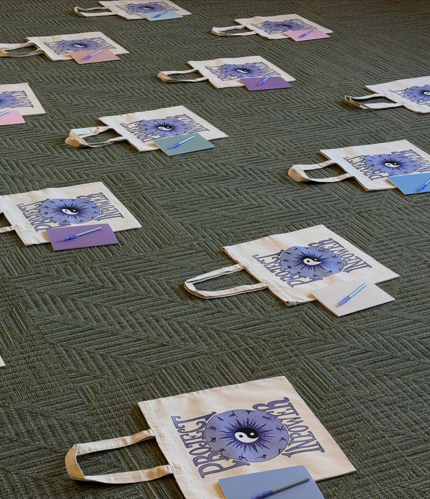 Project InPower tote bags with notebooks and pens laid out for survivors