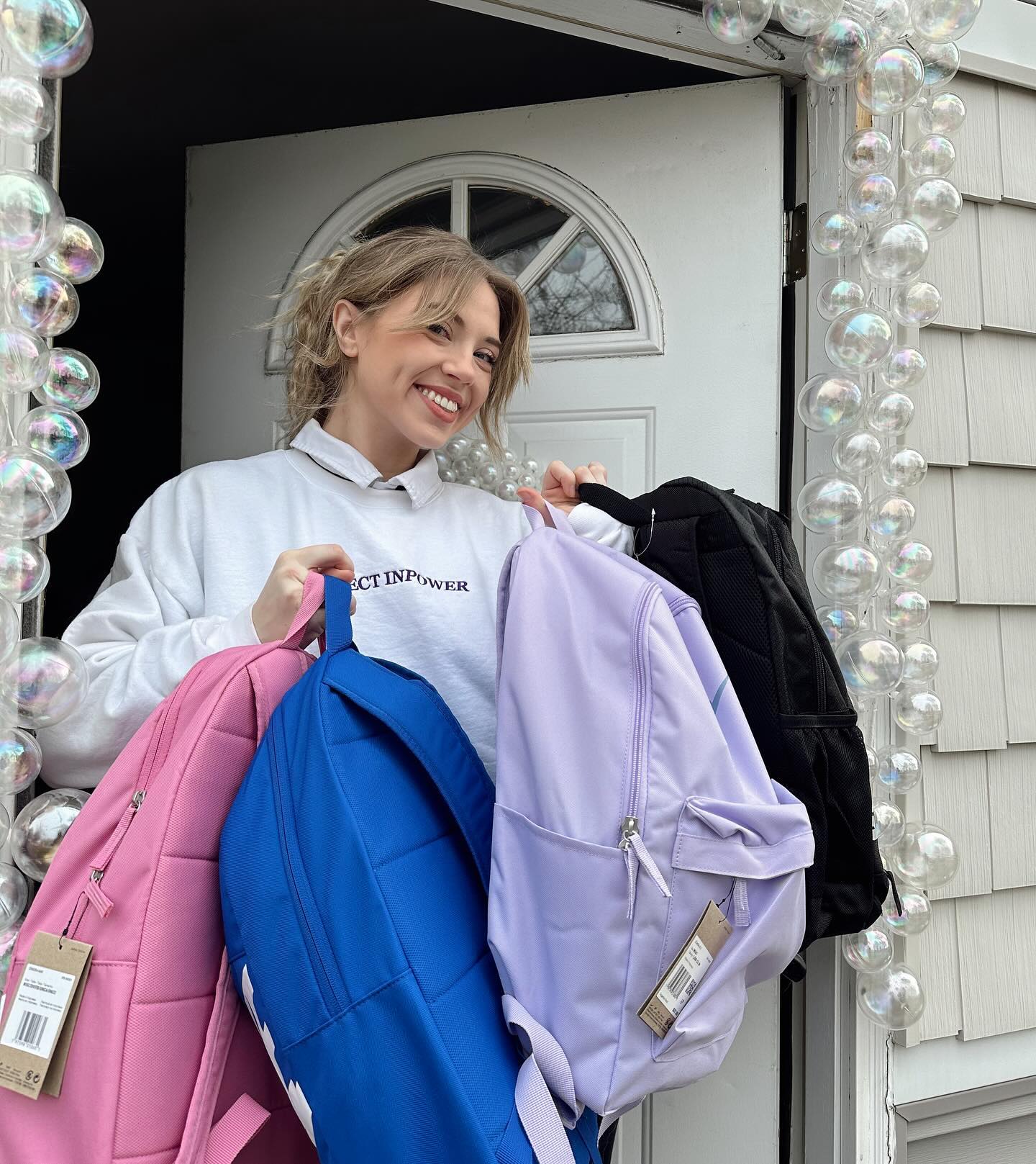 A Project InPower volunteer holding donated backpacks